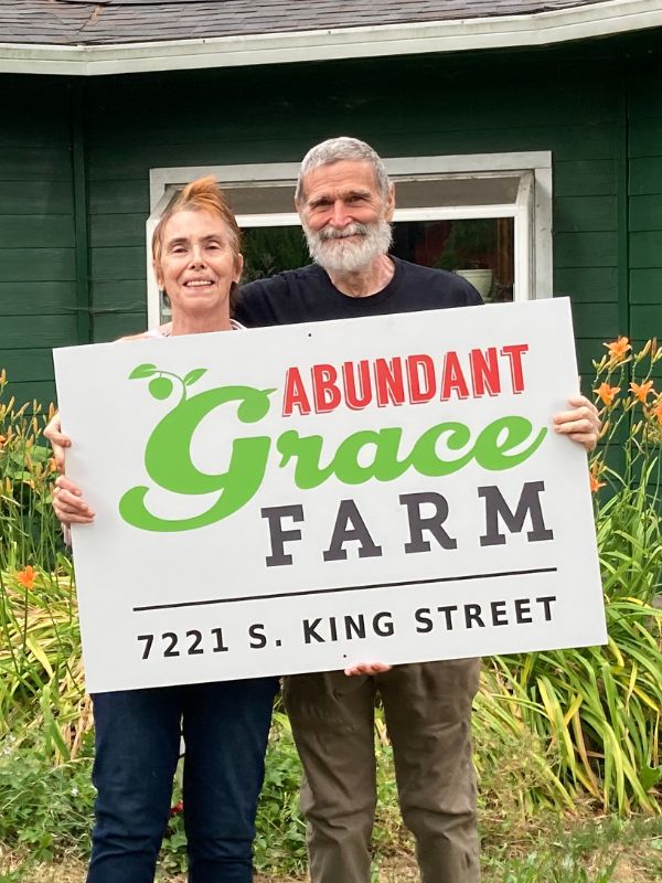 Jim and Alice holding Abundant Grace Farm sign